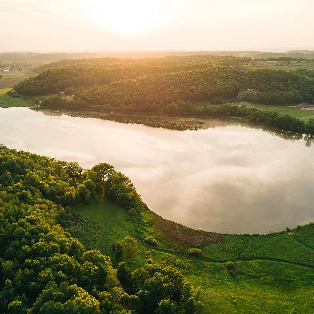 a lake at sunrise with greenery around it